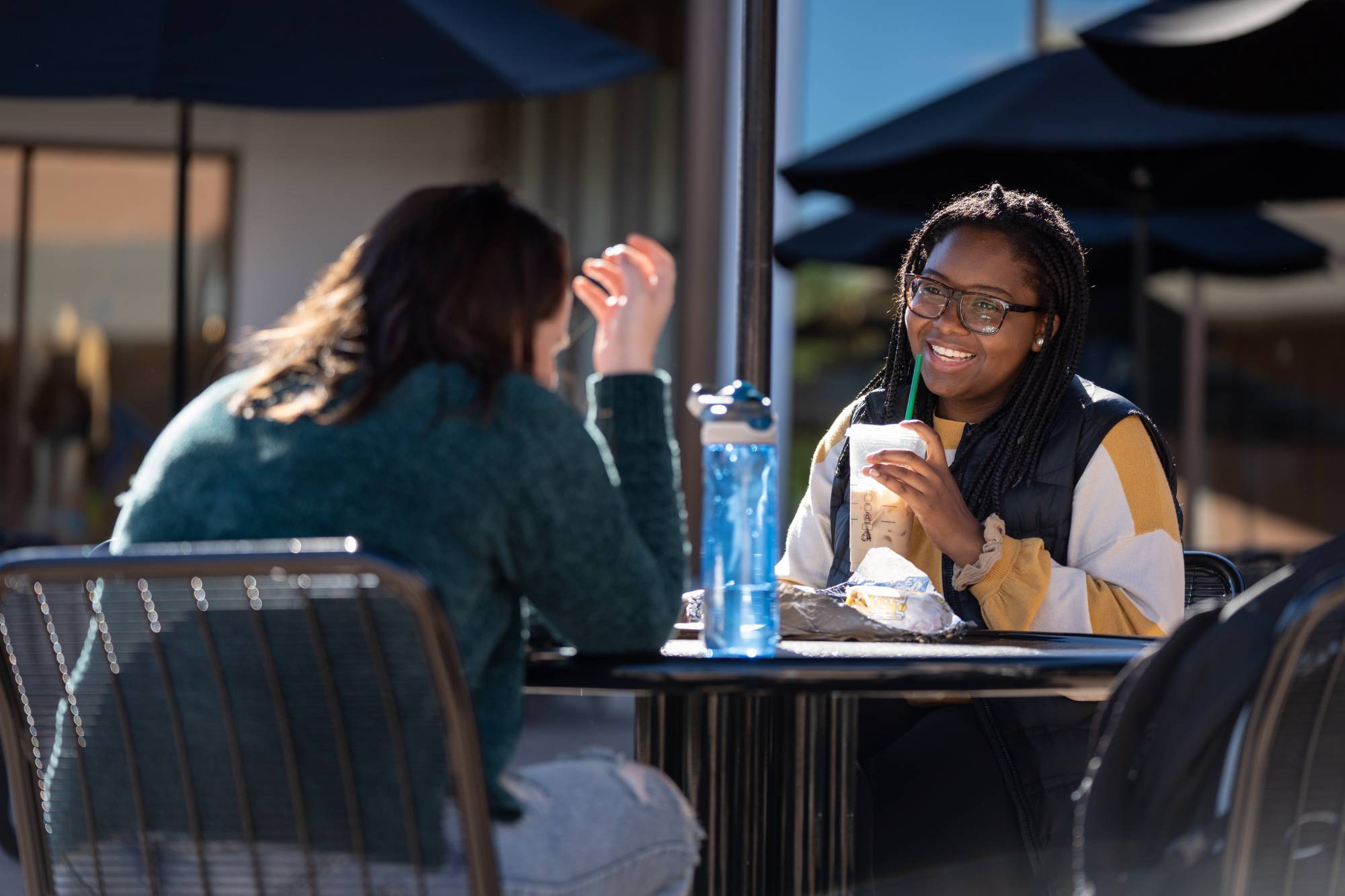 Students sitting at a table laughing and drinking coffee